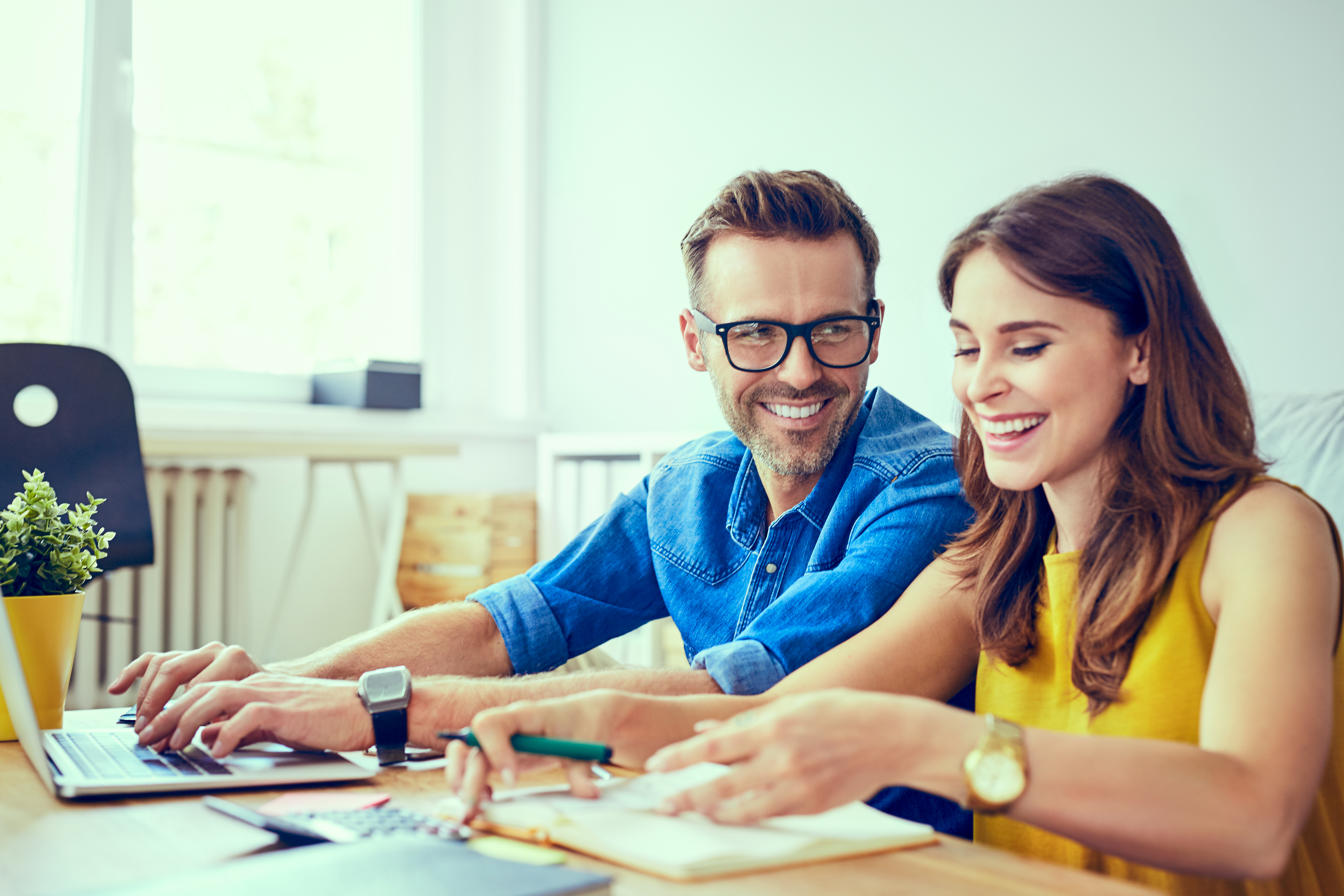 Happy couple at home paying bills with laptop