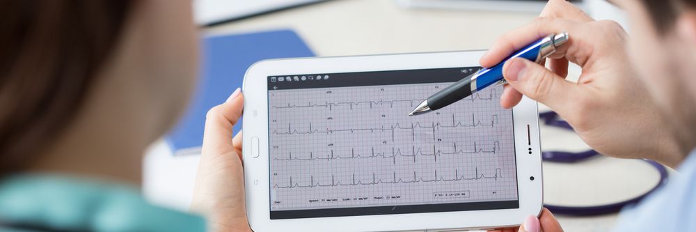 Two cardiologists review an ECG demonstrating ST-segment elevation on a tablet.