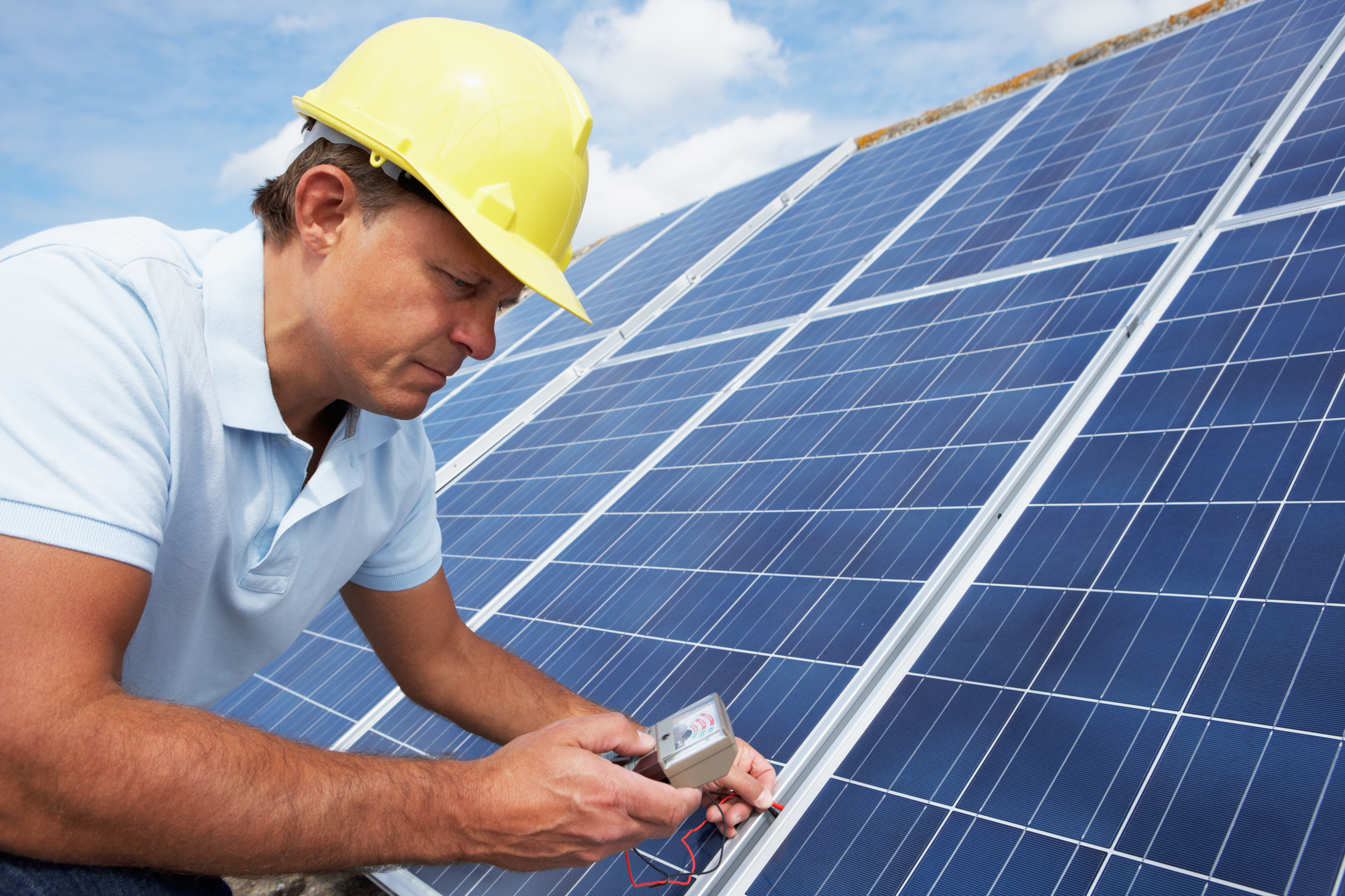 Man wearing hard hat checking roof solar panels