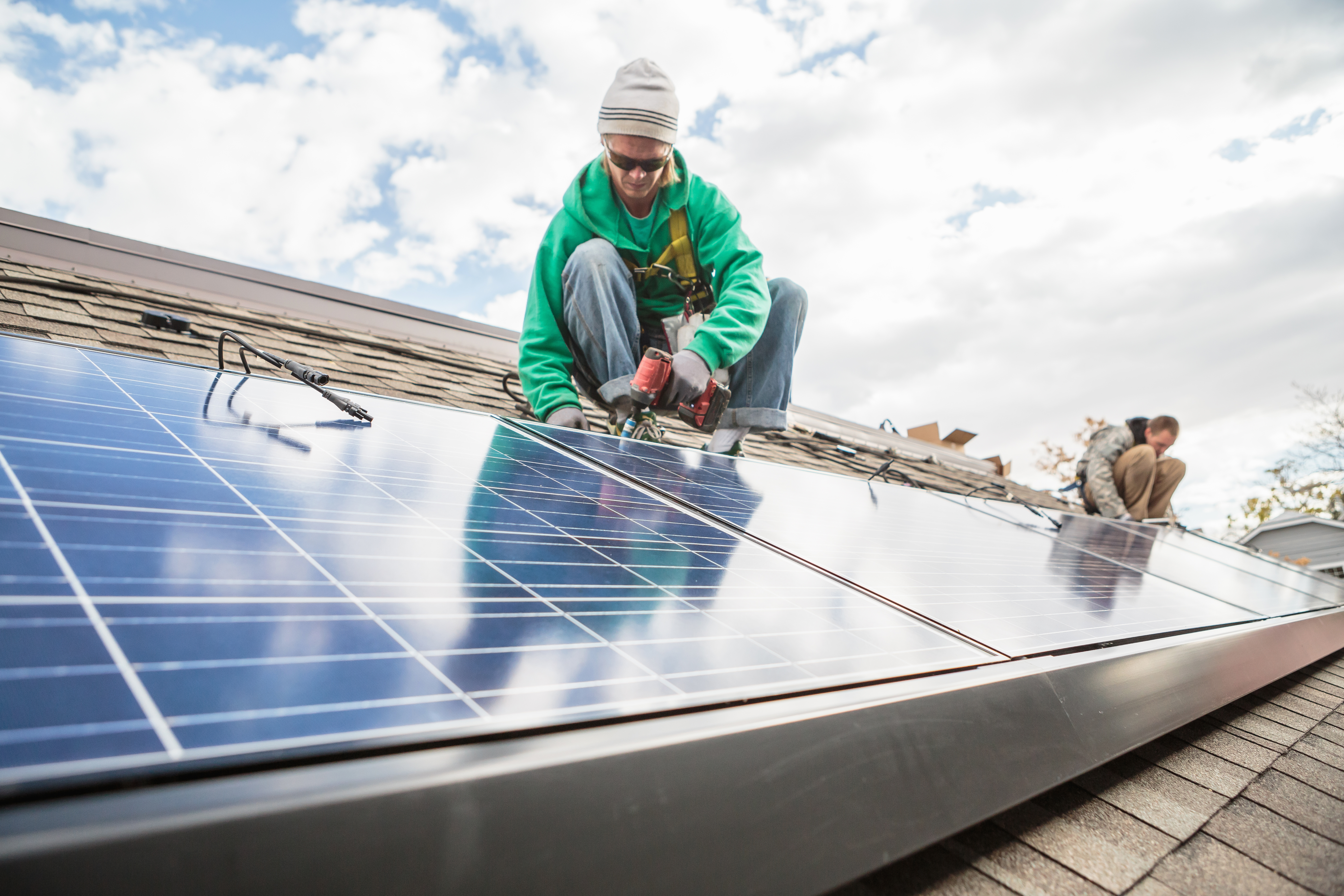 Construction crew installing solar panels on a house