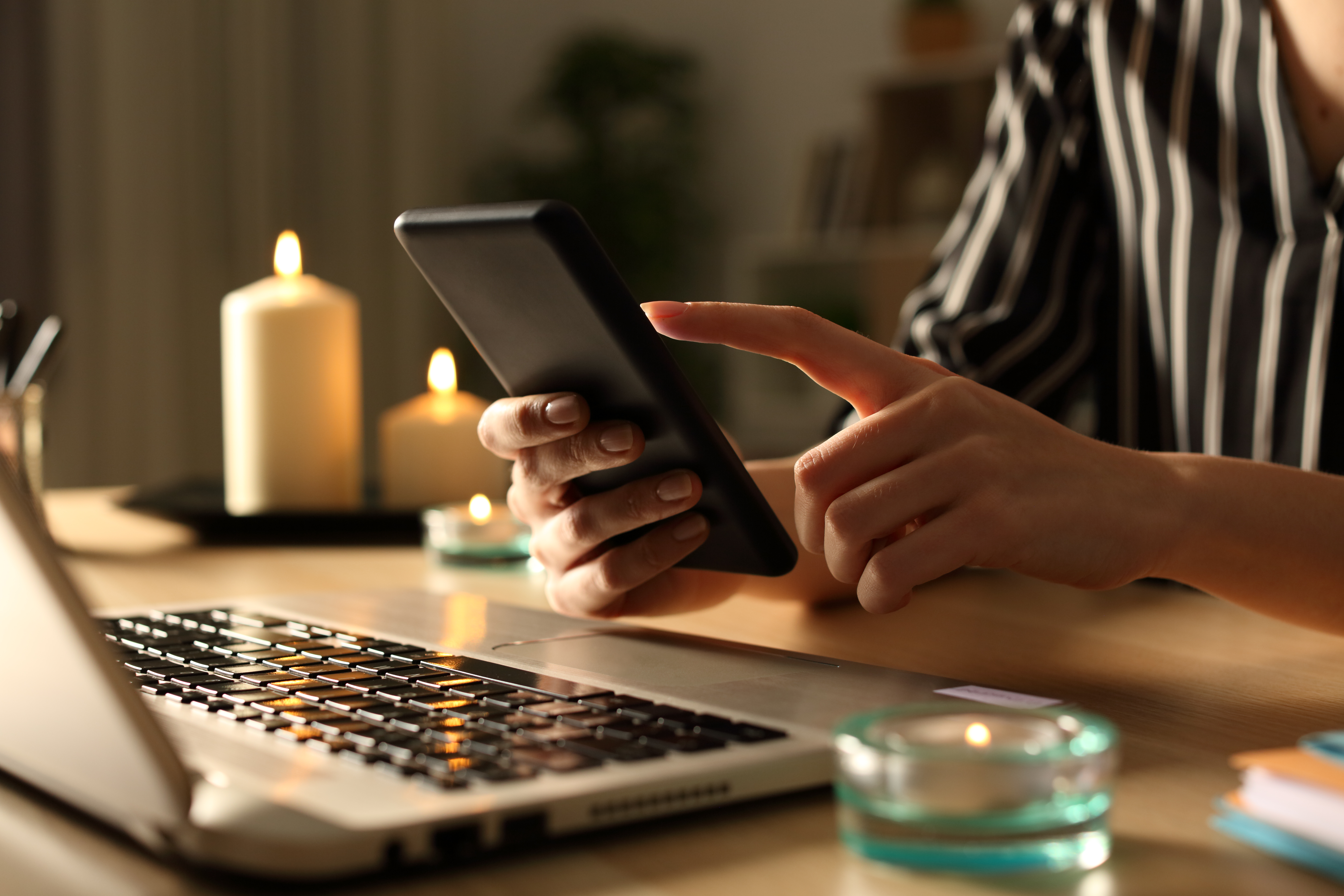 Girl hands using phone on power outage with candles