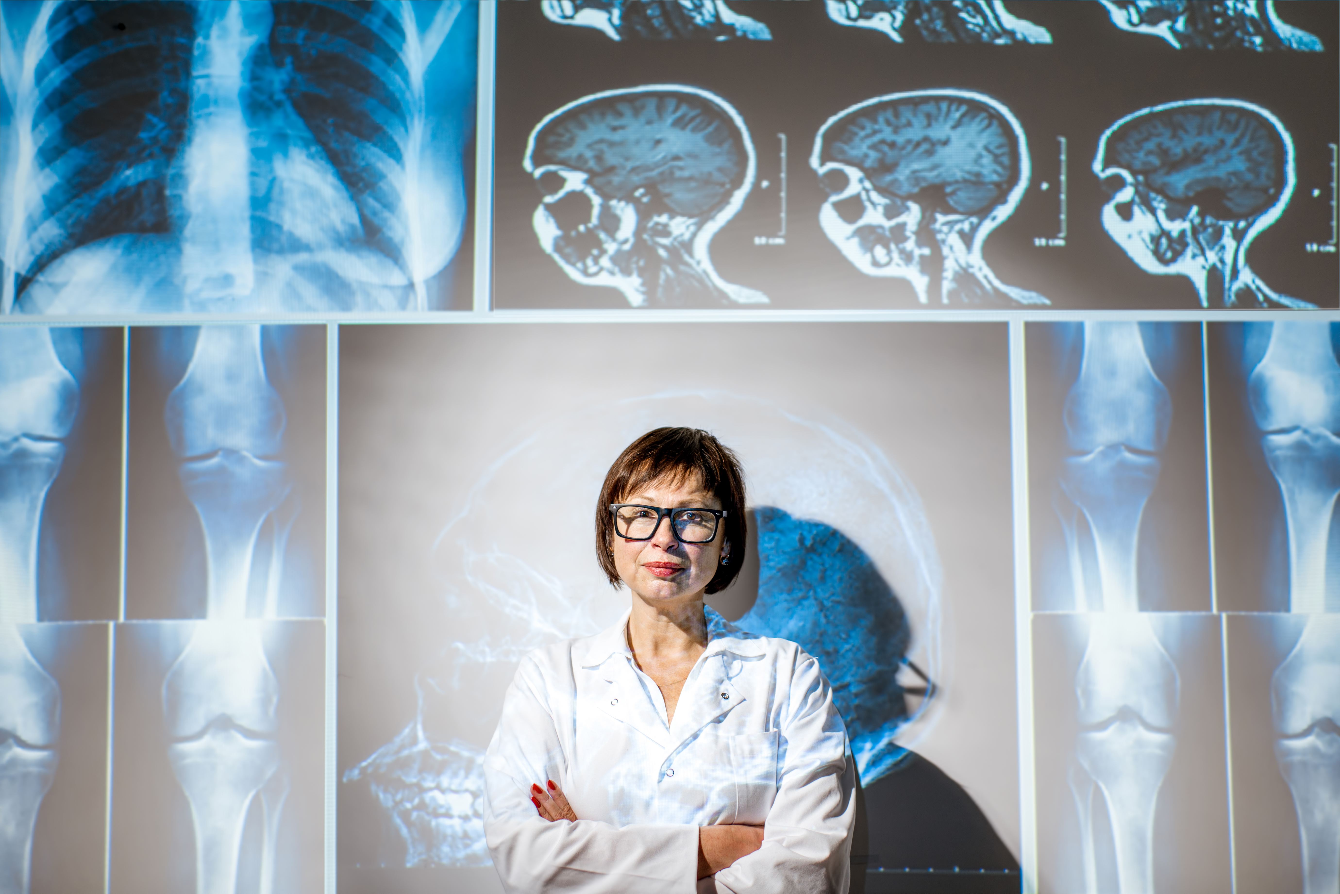 Portrait of a senior woman doctor in uniform with projected x-rays of human parts