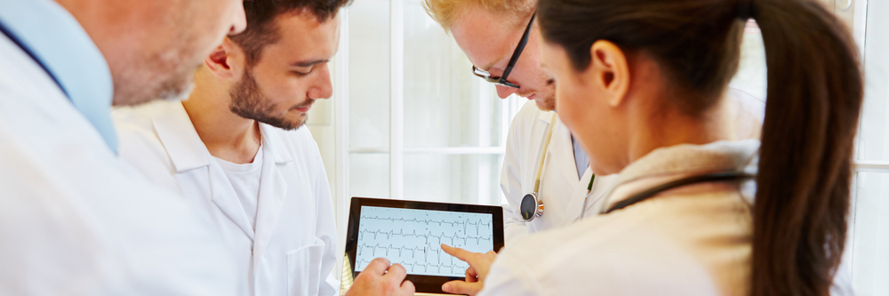 A team of cardiologists in a hospital reviews an ECG for underlying atrial fibrillation.