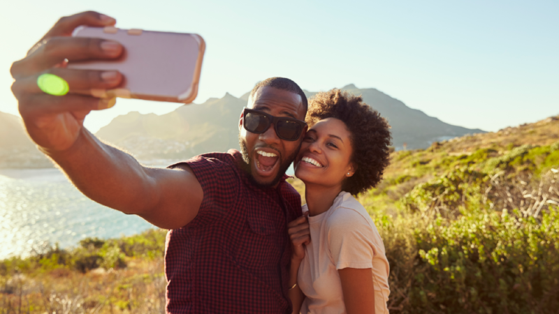 Young Couple Pose For Holiday Selfie On Clifftop