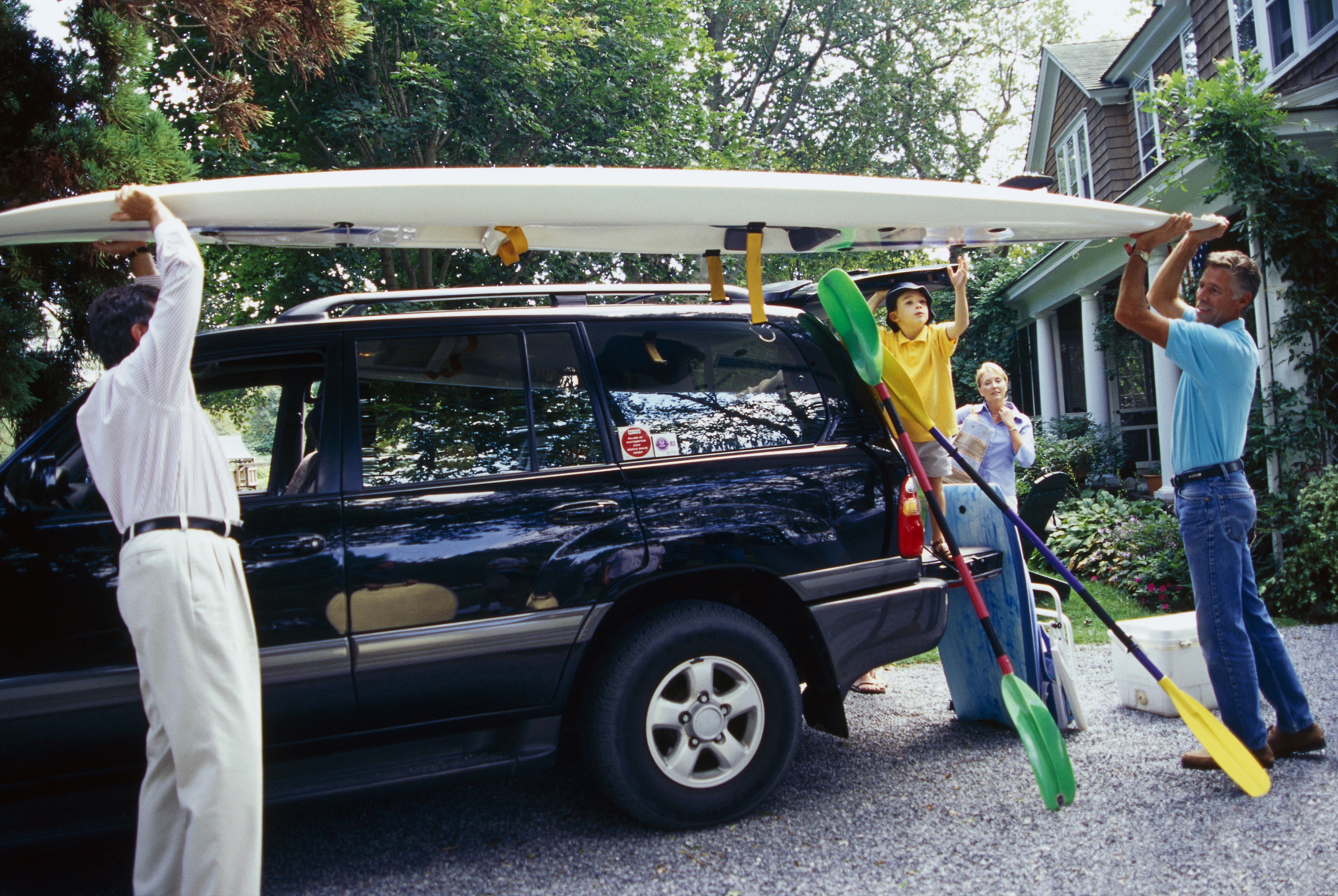 Family putting kayak on car