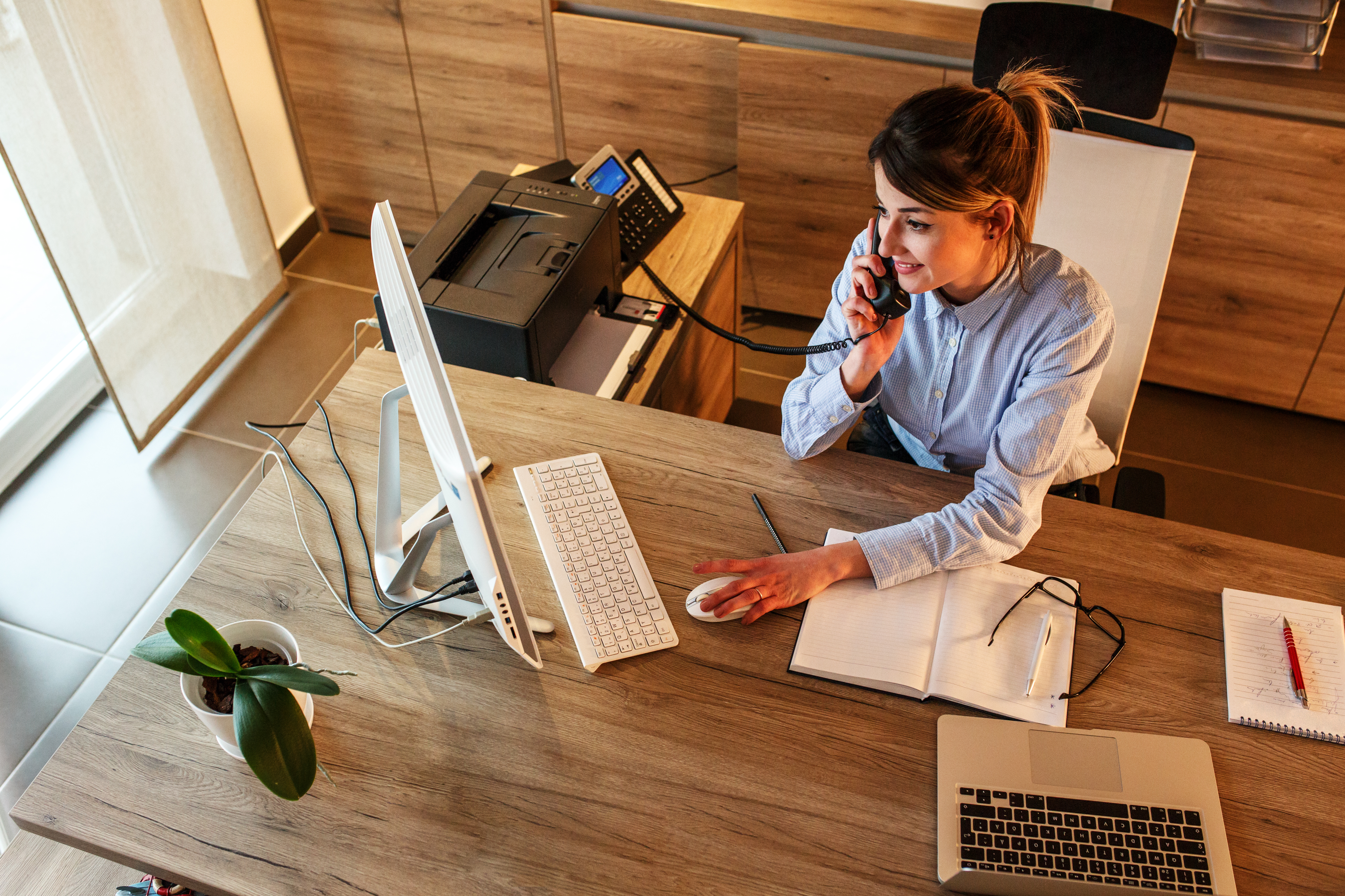 Businesswoman in her office.She sitting at the desk and talking on the phone.