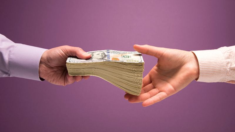 Man and woman's hands handing pile of cash