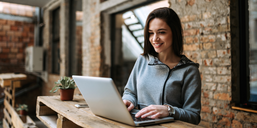 Portrait of a joyful young woman using laptop computer.