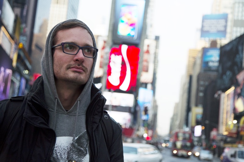 David Farrier, Director of HBO&squot;s "Tickled" stands in Times Square wearing a hooded sweatshirt