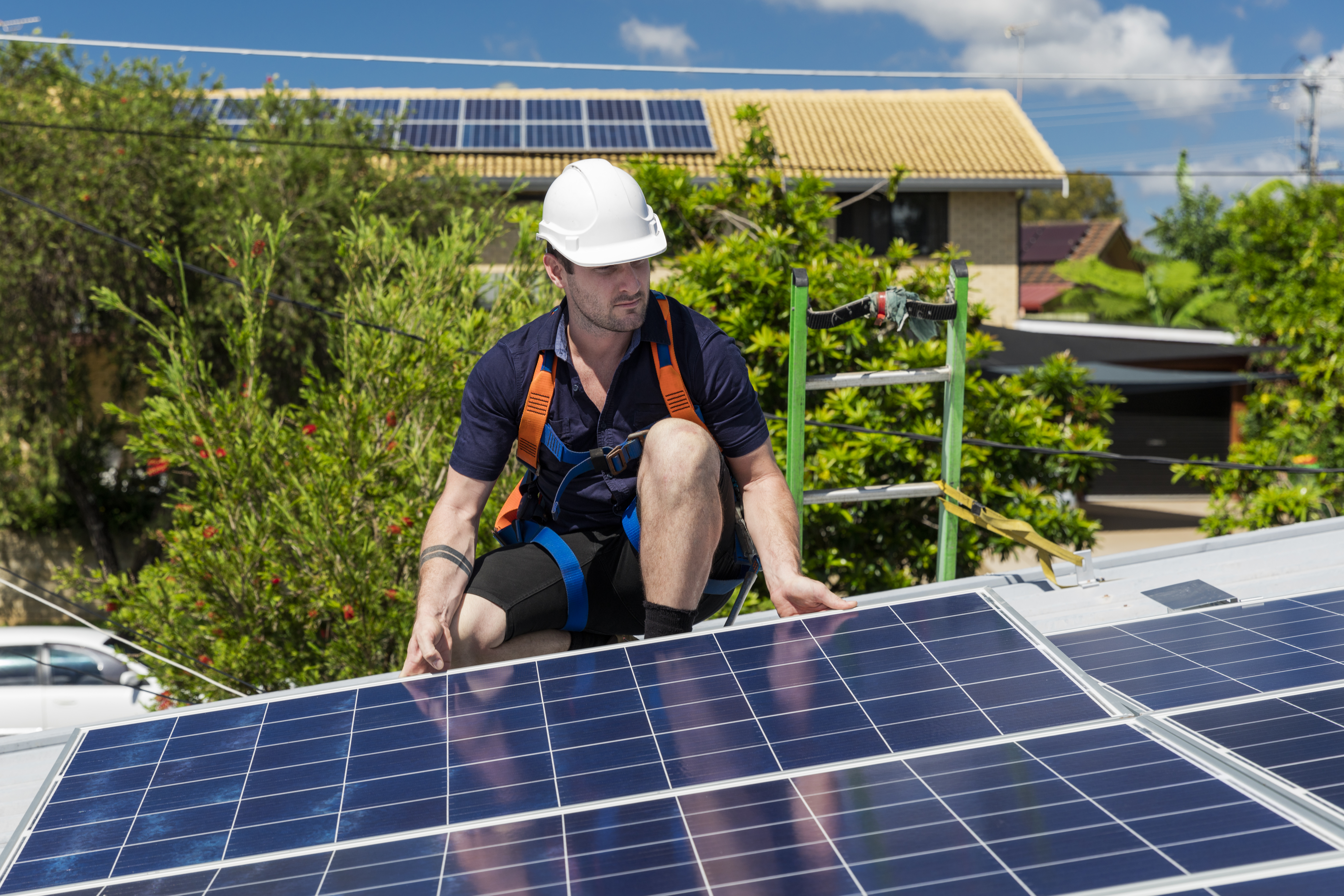 Solar panel technician with drill installing solar panels on roof