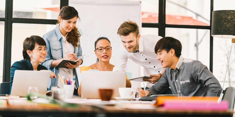 Multiethnic team busy discussion using laptop, digital tablet. Coworker partnership, college student meeting. Small business casual office, freelance designer job, or online marketing analysis concept