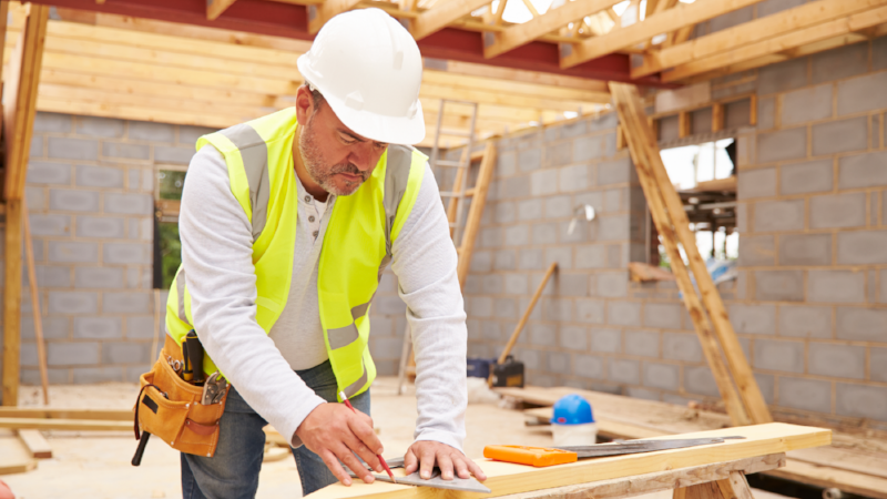 Carpenter Cutting House Roof Supports On Building Site