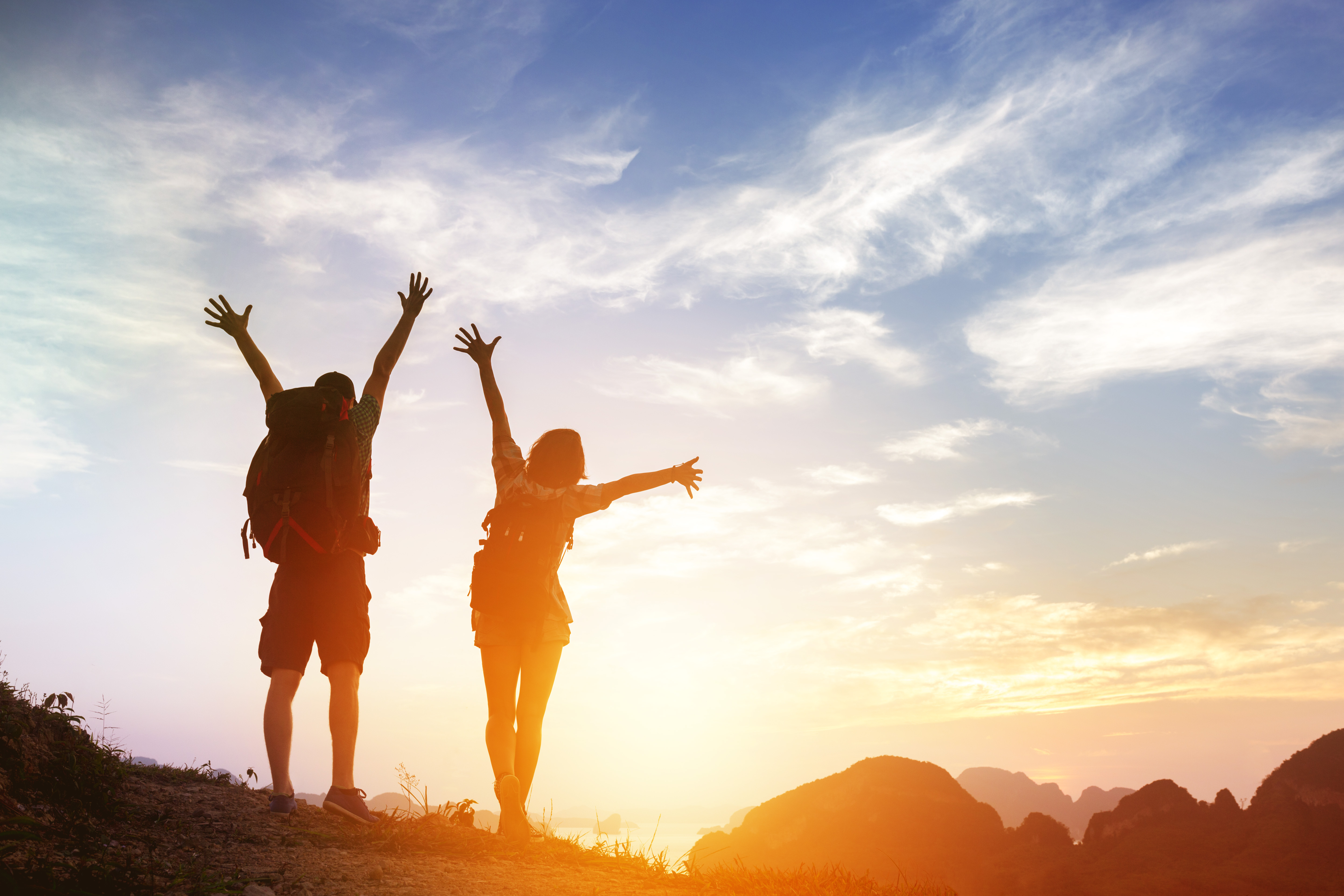 Two happy tourists greetings sunrise in mountains