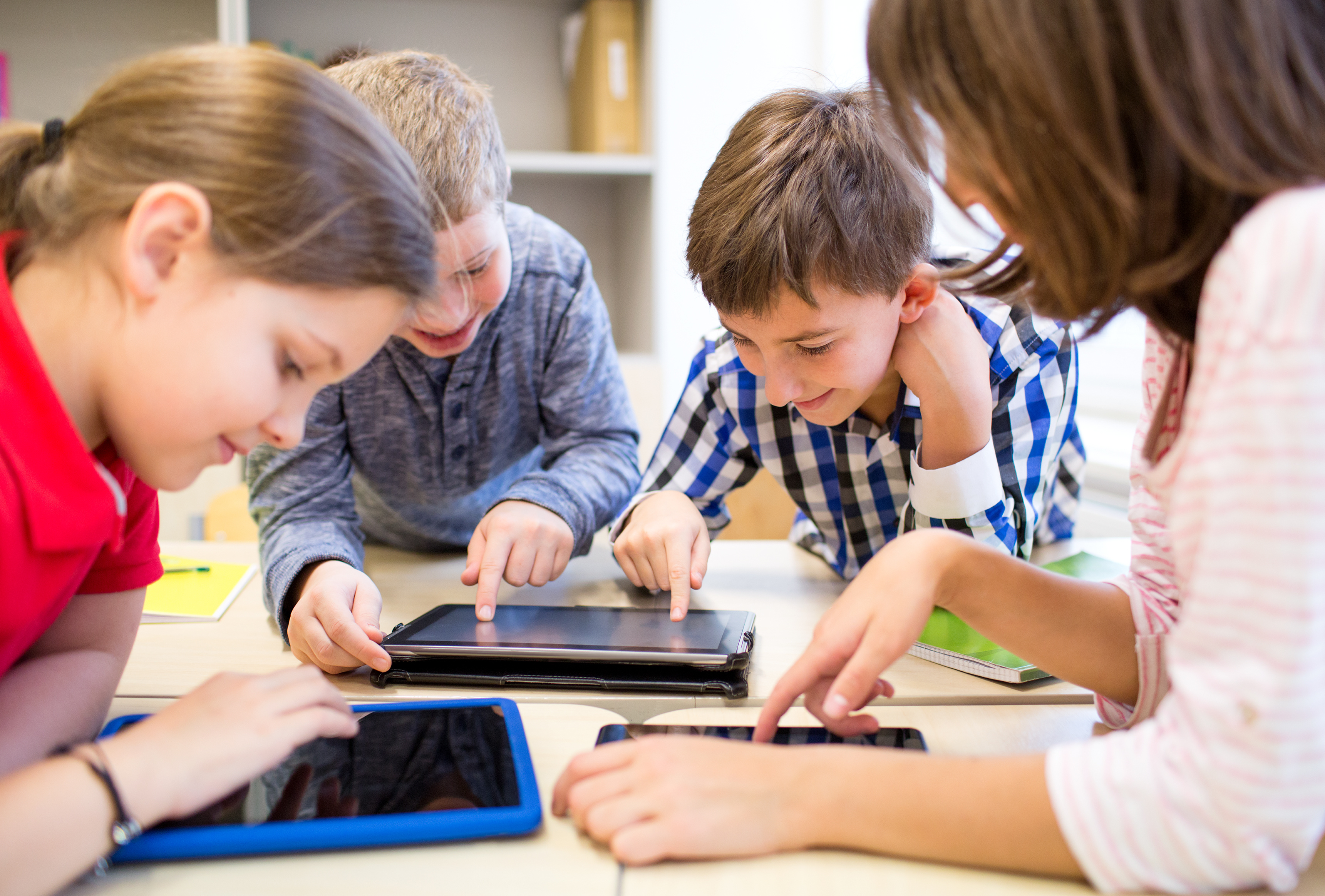 group of school kids with tablet device in classroom