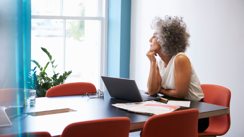 Middle aged woman looking out of the window in the boardroom