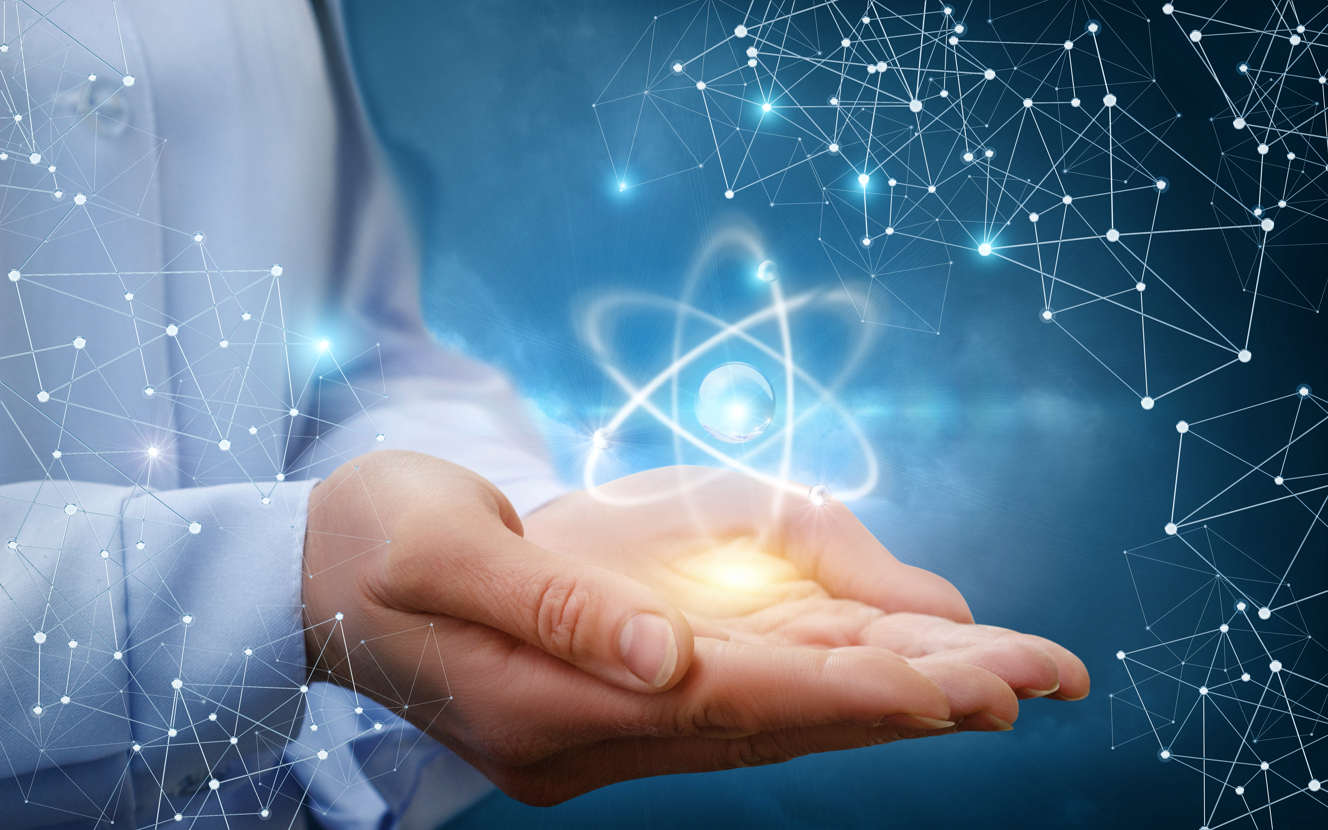 Atom molecule in female hands on a blue background.