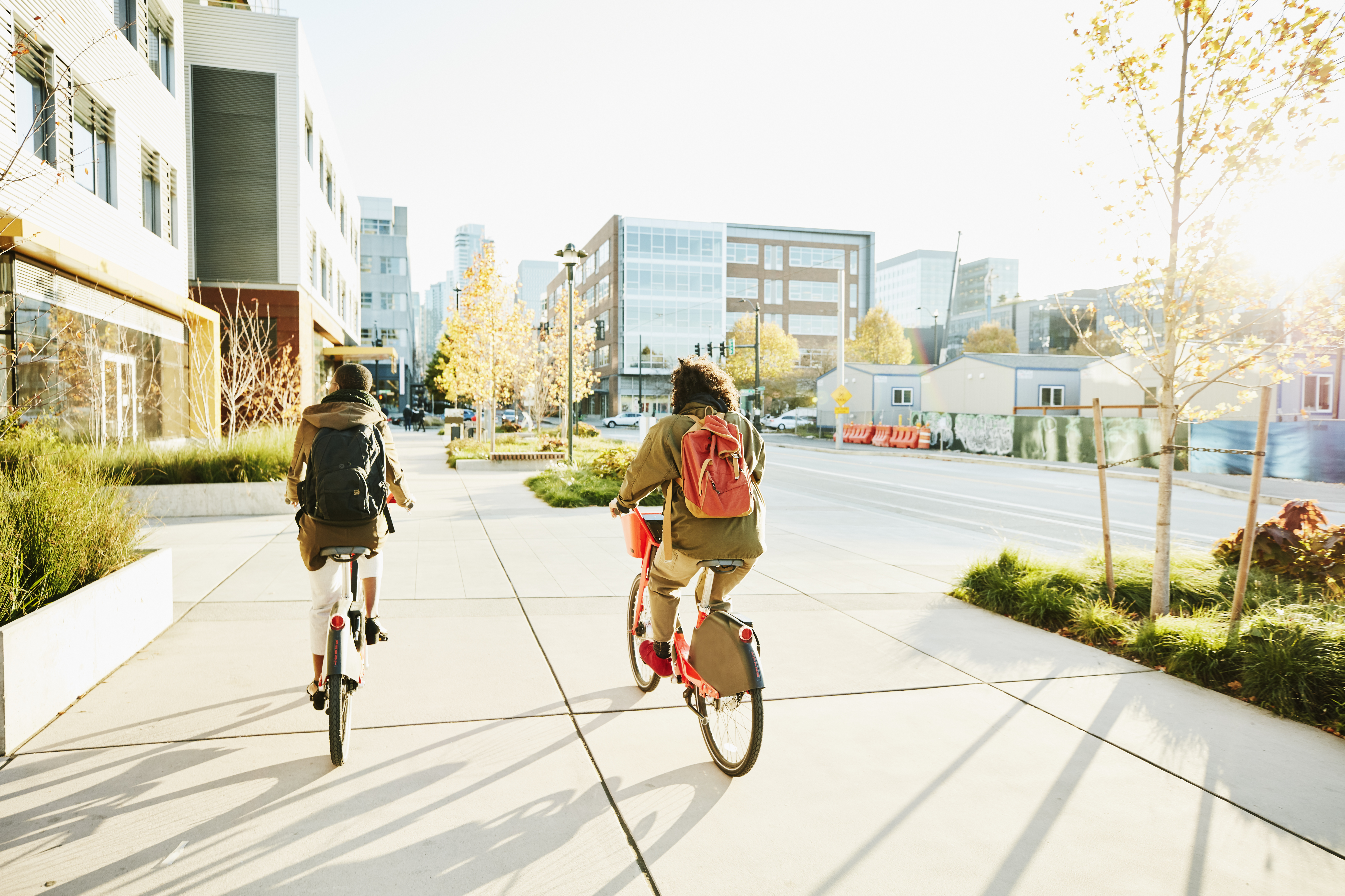 Rear view of friends commuting to work on electric bike share bikes