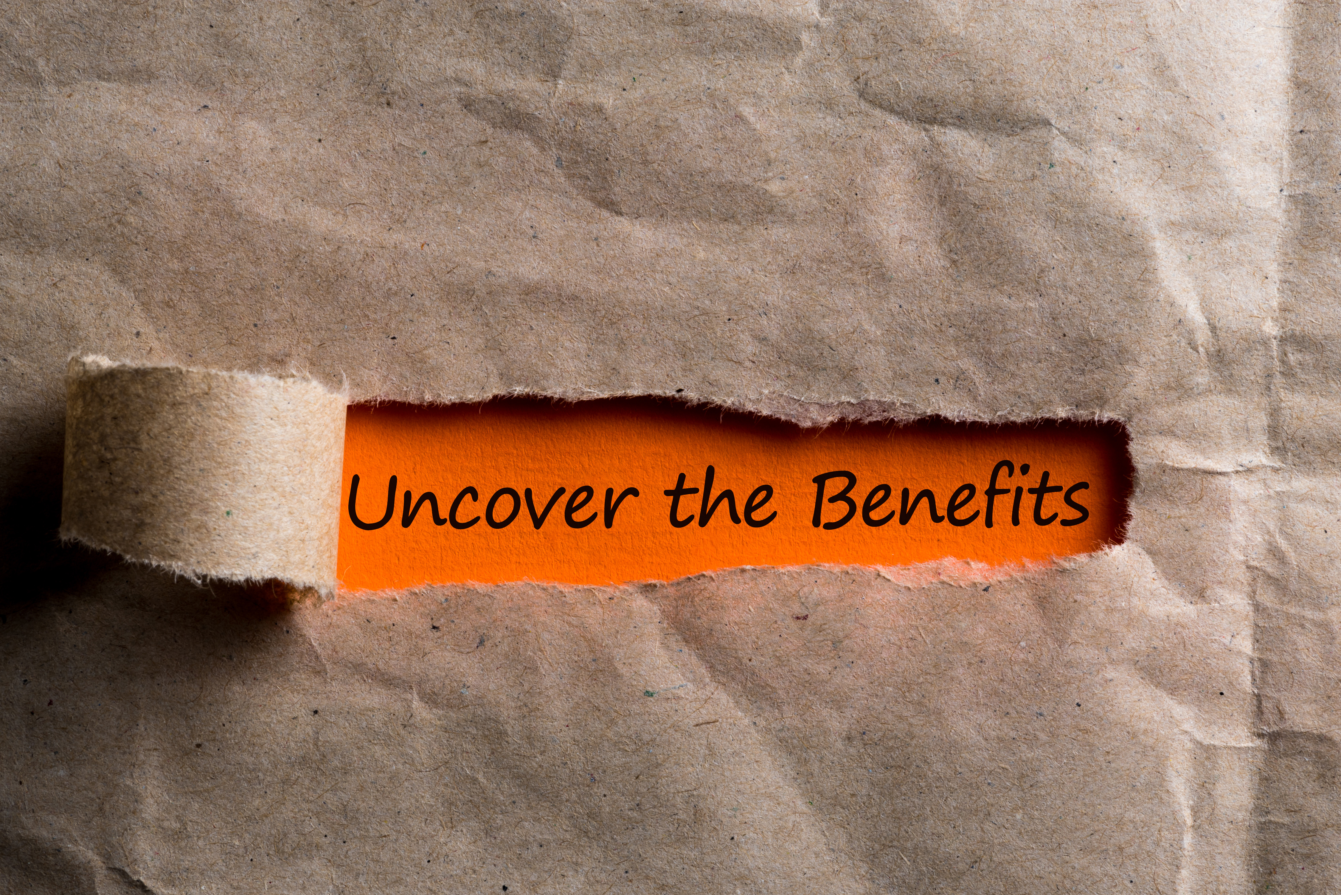 Uncover The Benefits message in letter or note, appearing behind ripped brown paper of envelope