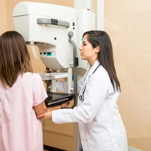 Pretty female doctor setting a patient in the correct position to get a mammogram in a clinic