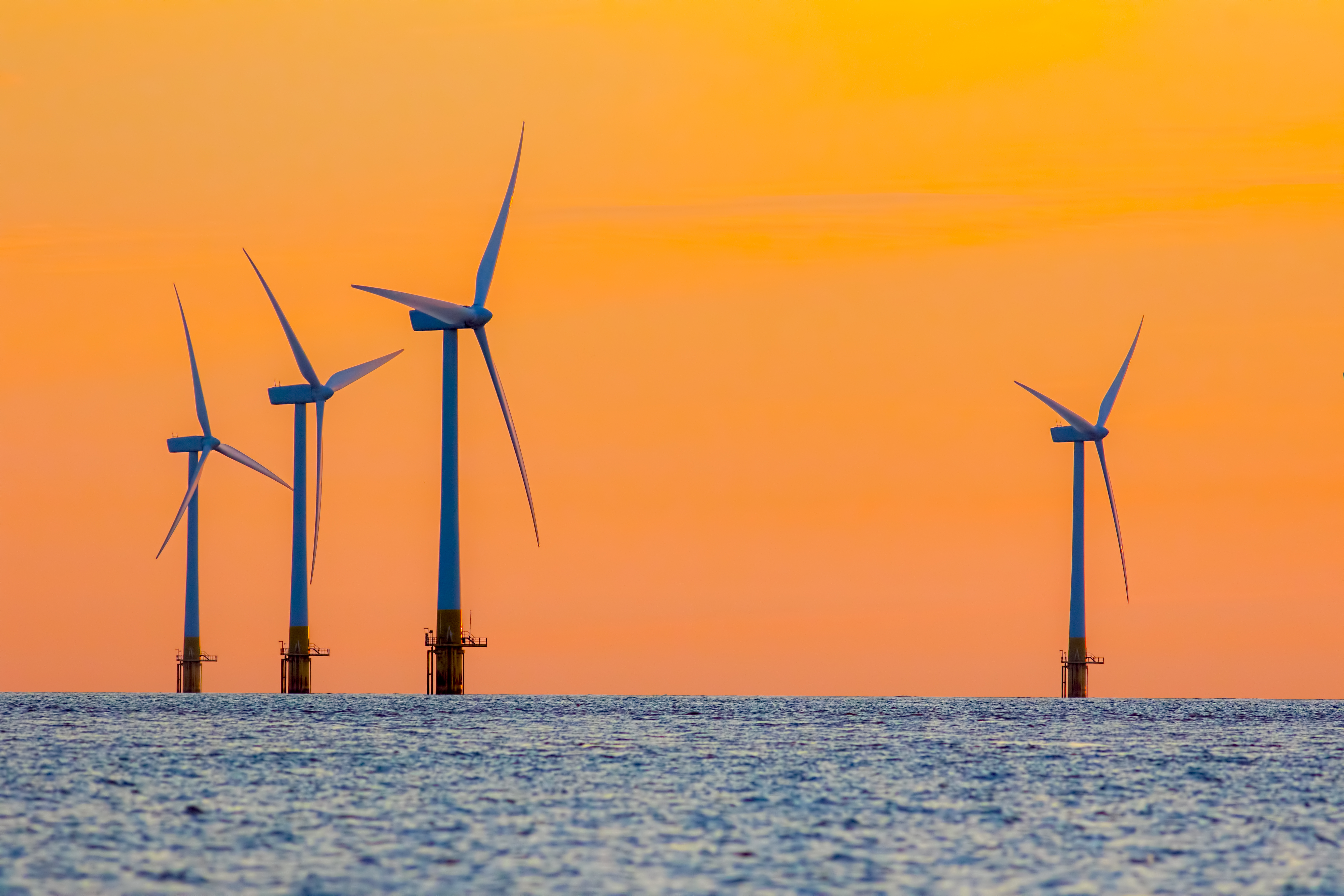 Offshore wind farm energy turbines at dawn. Surreal but natural sunrise at sea.