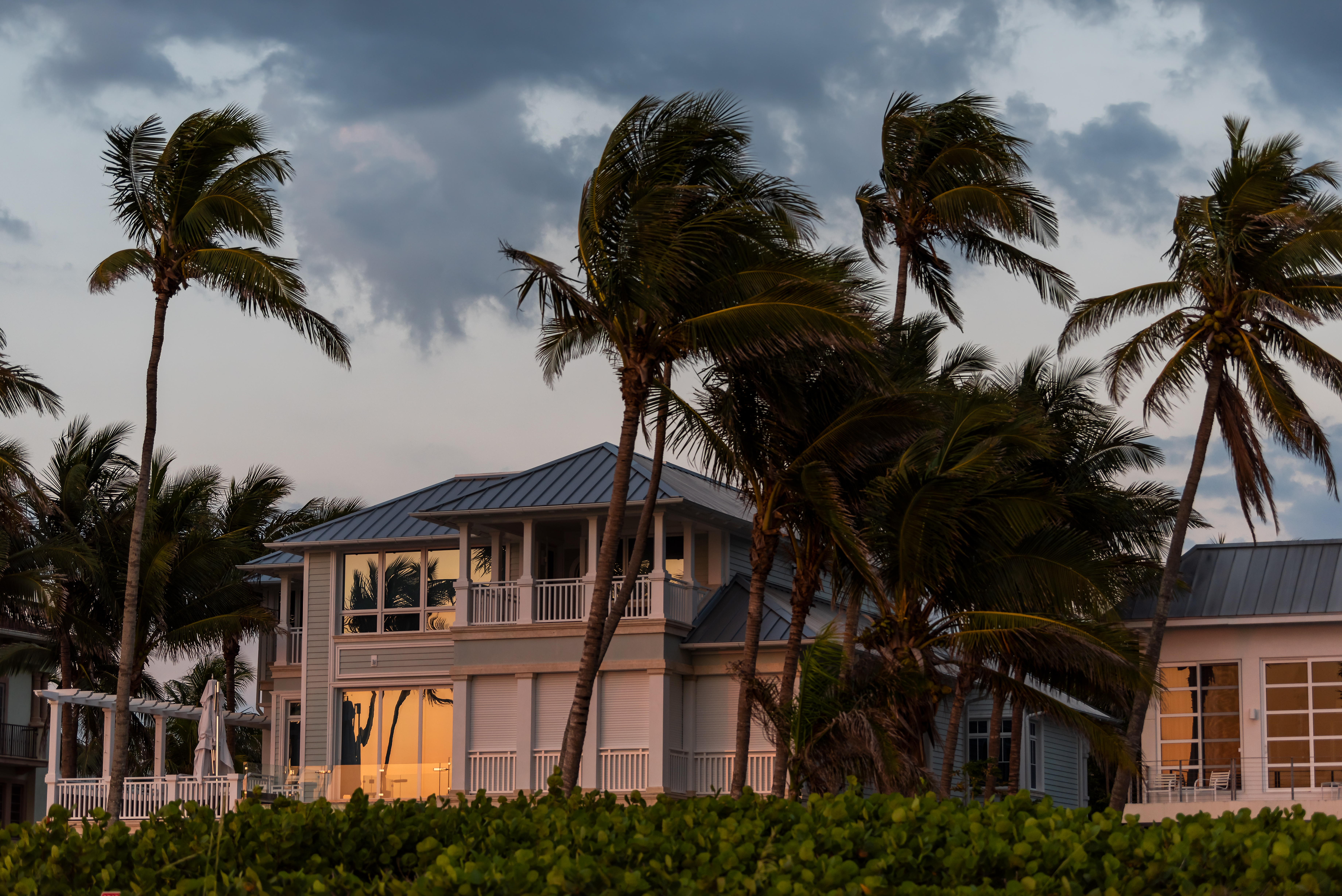 Coast house beachfront waterfront vacation home, house during evening sunset with nobody in Florida, gulf of mexico, storm weather and wind palm trees