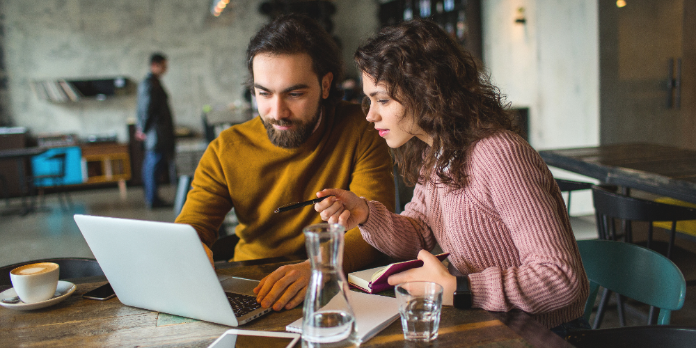 Young hipster male and female working laptop together in cafe